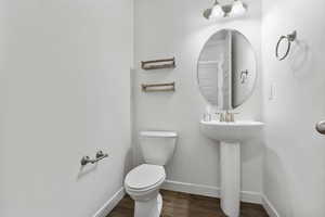 Bathroom with baseboards, a sink, toilet, and wood finished floors