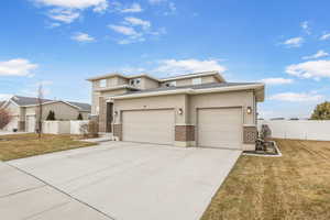 Prairie-style home featuring an attached garage, brick siding, fence, driveway, and a front yard