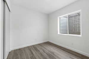 Unfurnished bedroom featuring a closet, baseboards, and wood finished floors