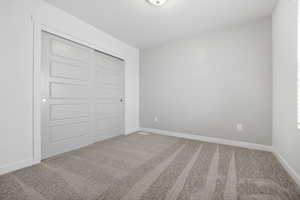 Unfurnished bedroom with carpet, baseboards, and a closet