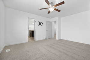 Unfurnished bedroom with light carpet, baseboards, visible vents, a ceiling fan, and connected bathroom