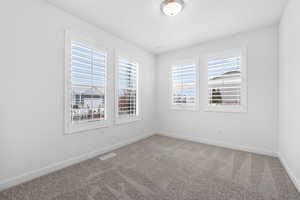 Carpeted spare room with visible vents and baseboards