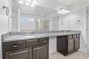 Bathroom with a stall shower, tile patterned flooring, a sink, and double vanity