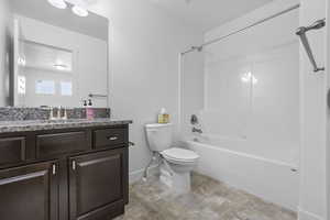 Full bathroom featuring baseboards, toilet,  shower combination, stone finish flooring, and vanity