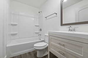 Full bathroom with shower / bathing tub combination, vanity, toilet, and wood finished floors