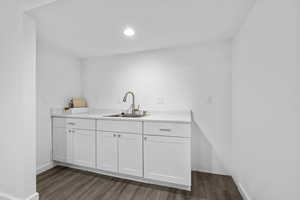 Kitchen with light countertops, dark wood-type flooring, a sink, and white cabinets