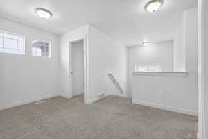 Basement featuring light carpet, plenty of natural light, and visible vents