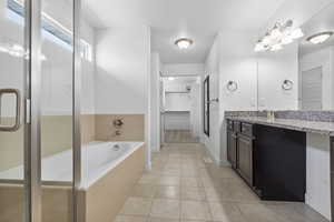 Bathroom featuring vanity, a bath, tile patterned floors, a stall shower, and a walk in closet