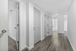 Hallway featuring visible vents, baseboards, and wood finished floors