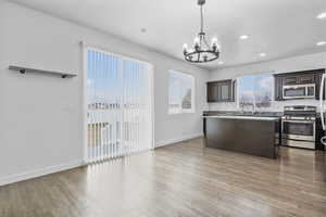 Kitchen with stainless steel appliances, light countertops, hanging light fixtures, and dark brown cabinetry