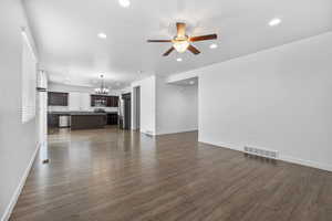 Unfurnished living room with recessed lighting, visible vents, dark wood finished floors, and ceiling fan with notable chandelier