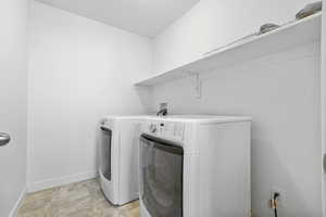 Washroom with laundry area, stone finish flooring, baseboards, and separate washer and dryer