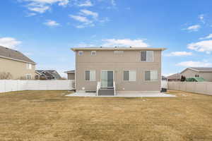 Rear view of house featuring entry steps, a yard, a patio area, and a fenced backyard