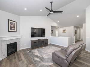 Living area with lofted ceiling, wood finished floors, a tile fireplace, and baseboards