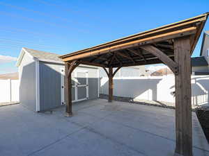 View of patio with an outbuilding, a storage unit, and a fenced backyard