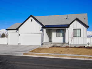 Modern farmhouse with an attached garage, driveway, a shingled roof, and board and batten siding