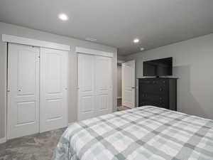 Bedroom featuring multiple closets, recessed lighting, visible vents, and light carpet