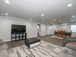 Living area with baseboards, an AC wall unit, wood finished floors, and recessed lighting