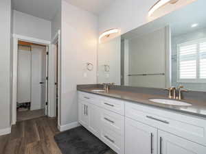 Bathroom featuring wood finished floors, a sink, baseboards, and double vanity