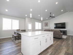 Kitchen featuring a center island, dark wood-style flooring, decorative light fixtures, light countertops, and white cabinets