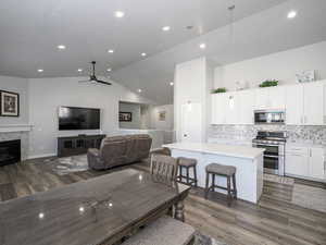 Dining room with lofted ceiling, a fireplace, wood finished floors, and recessed lighting