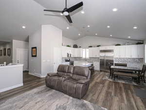 Living area with dark wood-style floors, lofted ceiling, visible vents, a ceiling fan, and baseboards