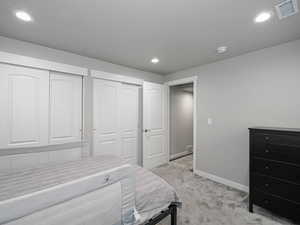 Bedroom featuring two closets, recessed lighting, light colored carpet, visible vents, and baseboards