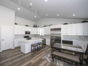 Kitchen featuring a center island, hanging light fixtures, stainless steel appliances, light countertops, and white cabinetry