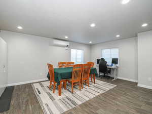 Dining space with dark wood-style floors, baseboards, an AC wall unit, and recessed lighting