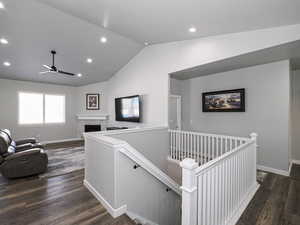 Hall with lofted ceiling, baseboards, dark wood-type flooring, and an upstairs landing