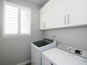 Laundry room featuring baseboards, cabinet space, and washing machine and clothes dryer