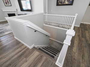 Stairs with a tiled fireplace, wood finished floors, and baseboards