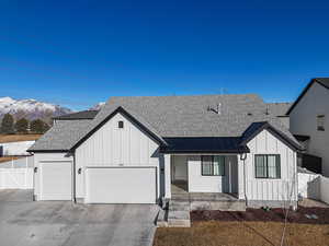 Modern farmhouse style home with a shingled roof, an attached garage, a standing seam roof, a mountain view, and board and batten siding