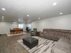 Living area featuring recessed lighting, baseboards, wood finished floors, and a wall mounted air conditioner