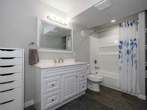 Bathroom featuring visible vents, toilet, wood finished floors, shower / bath combination with curtain, and vanity