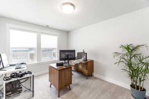 Office area featuring light carpet, visible vents, and baseboards