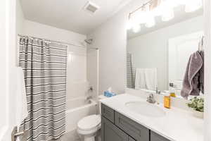 Full bathroom featuring shower / tub combo, visible vents, vanity, and toilet