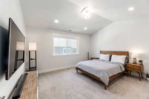 Bedroom with lofted ceiling, recessed lighting, light colored carpet, visible vents, and baseboards