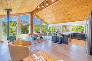 Living area featuring a wood stove, wood ceiling with exposed beams, light wood finished floors, and high vaulted ceiling
