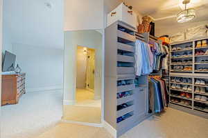 Spacious closet with an inviting chandelier and light colored carpet