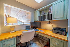 Office area featuring vaulted ceiling, built in desk, and wooden ceiling