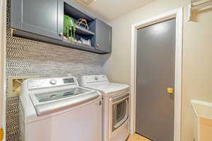 Clothes washing area featuring cabinet space, visible vents, and separate washer and dryer