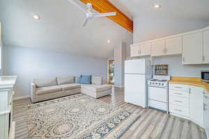 Kitchen featuring white appliances, light countertops, open floor plan, and white cabinets