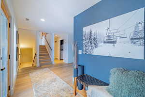 Living area featuring light wood-type flooring, visible vents, stairway, and recessed lighting