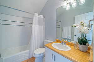 Full bathroom with shower / bath combination with curtain, a textured wall, toilet, and tile patterned floors