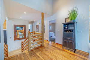 Hallway featuring light wood finished floors, an upstairs landing, visible vents, and recessed lighting