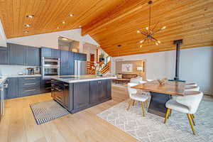 Kitchen featuring stainless steel appliances, light countertops, decorative light fixtures, and a kitchen island