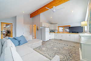 Living room with light wood-style floors, recessed lighting, vaulted ceiling with beams, and a ceiling fan