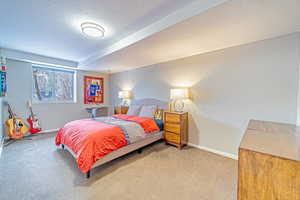 Carpeted bedroom with baseboards, a textured ceiling, and a textured wall