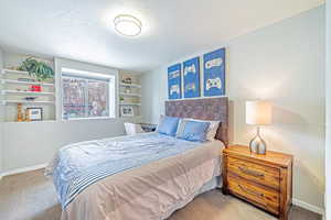 Carpeted bedroom with baseboards, a textured ceiling, and a textured wall